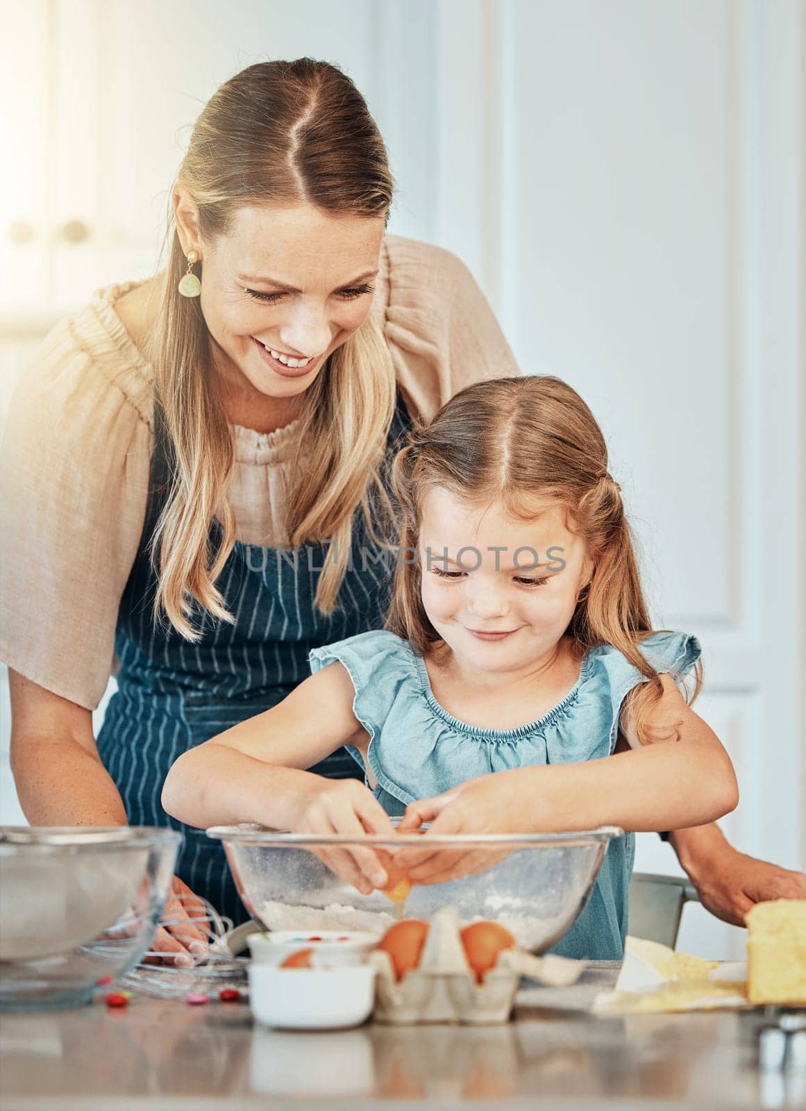 Mom, girl child and eggs in kitchen, development and skills with bonding, love or care in family house. Cooking, mother and daughter with smile, teaching and education by table, bowl or help for food.