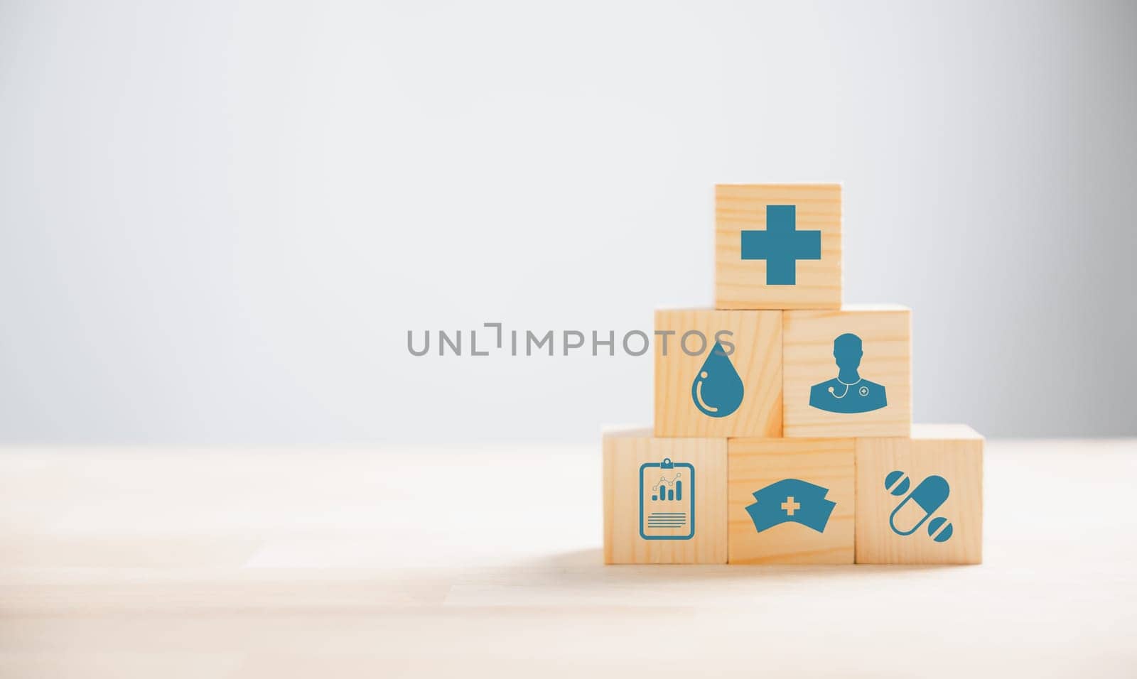 Pyramid wooden cubes, forming stack represents healthcare insurance concept. Medical icons atop, conveying protection and security. background provides copyspace for conveying Health Insurance ideas.