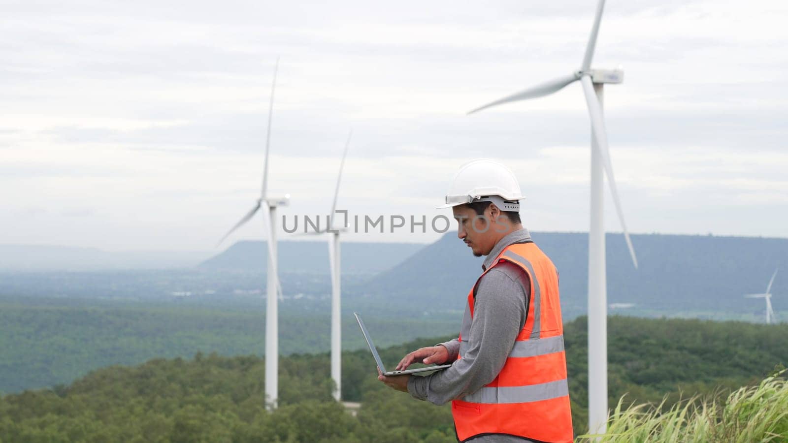 Engineer working on a wind farm atop a hill or mountain in the rural. Progressive ideal for the future production of renewable, sustainable energy. Energy generation from wind turbine.