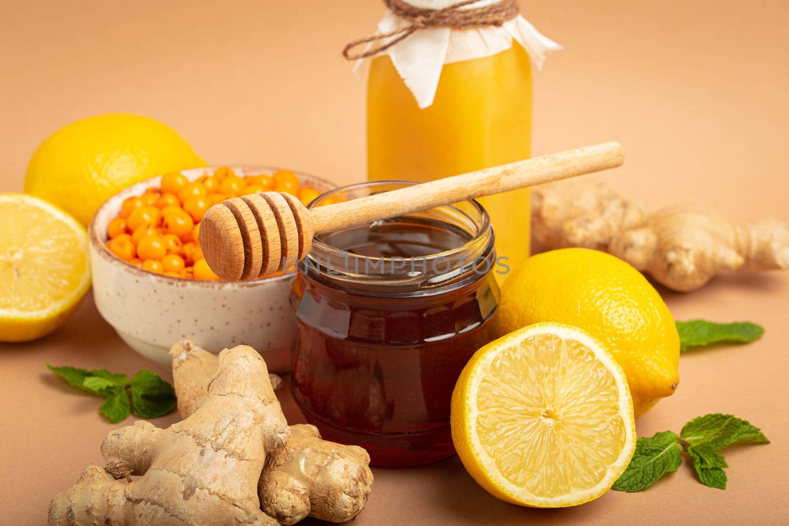 Composition with detox drink, sea buckthorn berries, lemons, mint, ginger, honey in glass jar. Food for immunity stimulation and against flu. Healthy natural remedies to boost immune system.