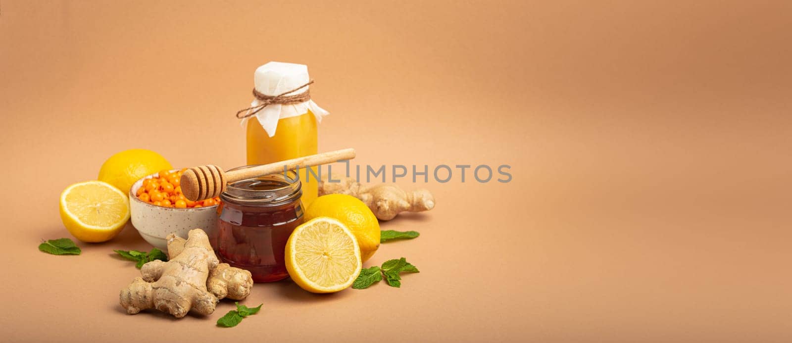 Composition with detox drink, sea buckthorn berries, lemons, mint, ginger, honey in glass jar. Food for immunity stimulation and against flu. Healthy natural remedies to boost immune system.