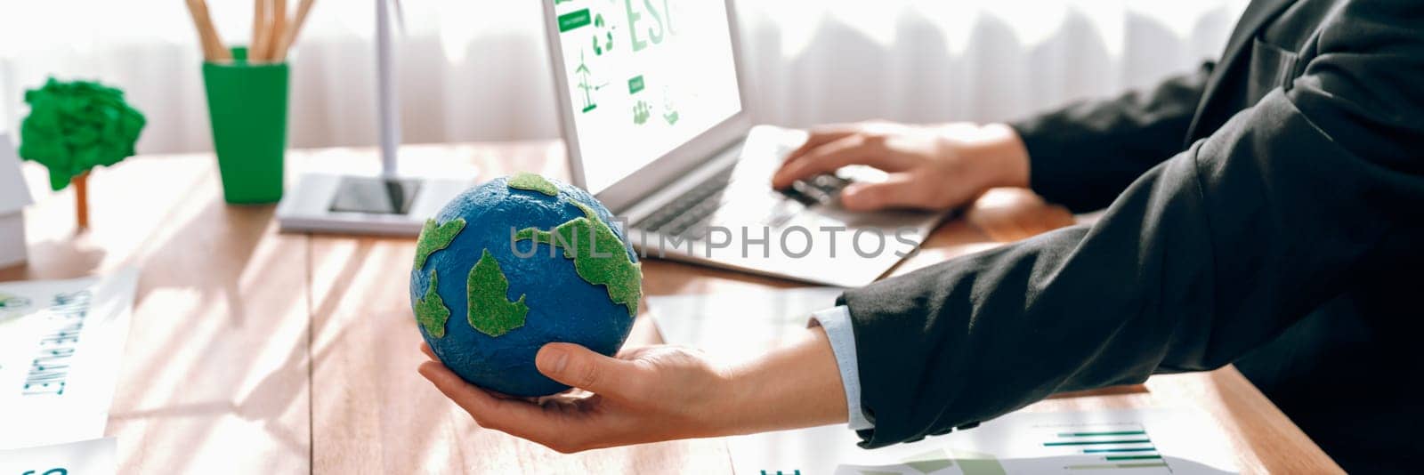 Businessman or CEO of the green corporate company holding paper Earth as concept for environmental friendly business to reduce CO2 emission and carbon footprint for cleann ecology. Trailblazing