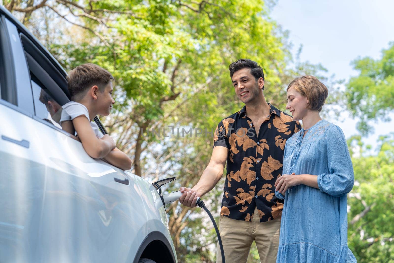 Family road trip vacation with electric vehicle, lovely family recharge EV car with green and clean energy. Natural and eco friendly car travel for sustainable environment. Perpetual