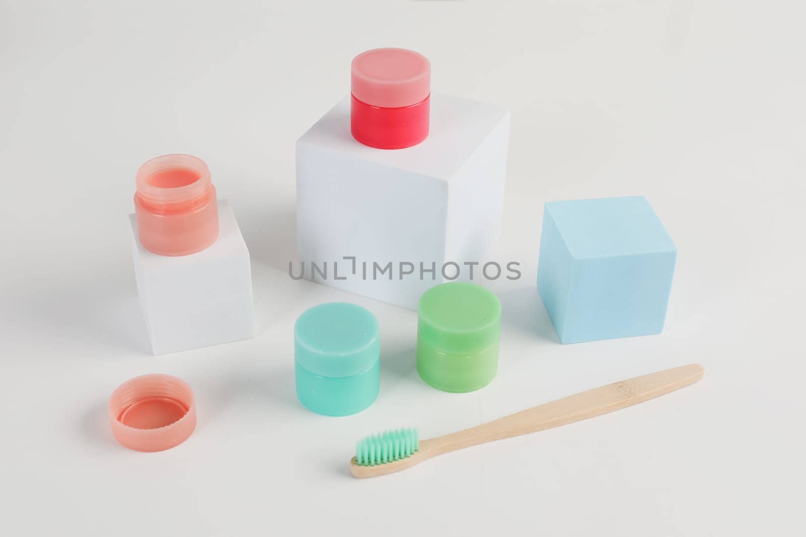 Colorful round jars of mask or lip balm and a brush. Female makeup, grooming product, decorative cosmetics, cosmetic products and tools isolated on white background