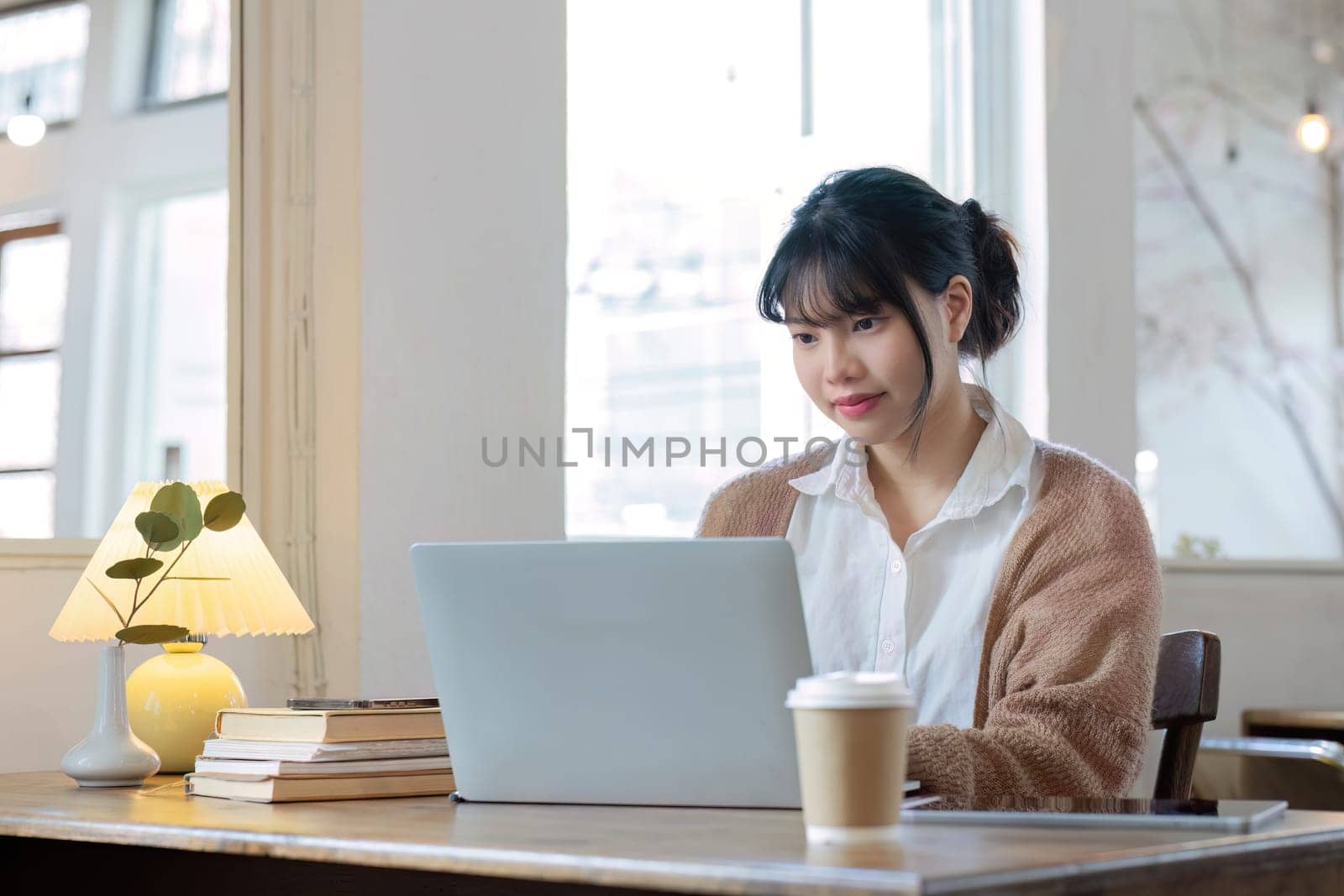 Asian female student studying online, studying on a video call, zoom call, passionate Asian female teacher learning English online with a laptop computer by wichayada