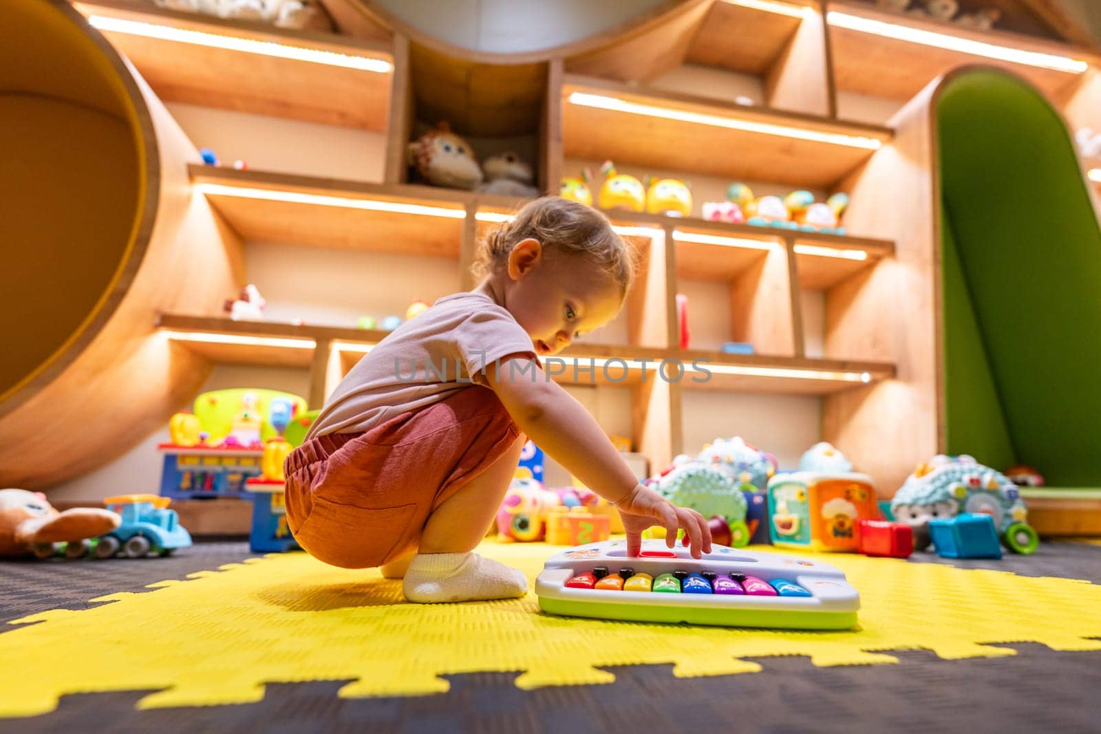 Child developing motor skills while playing with a musical toy in a bright playroom