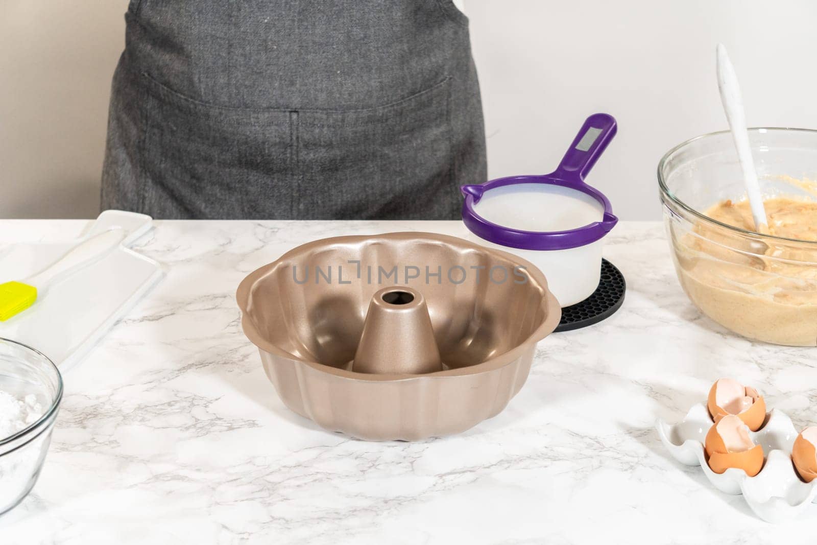 Using a silicone brush, the metal bundt cake pan is greased with melted vegetable shortening, preparing for baking the scrumptious Carrot Bundt Cake.