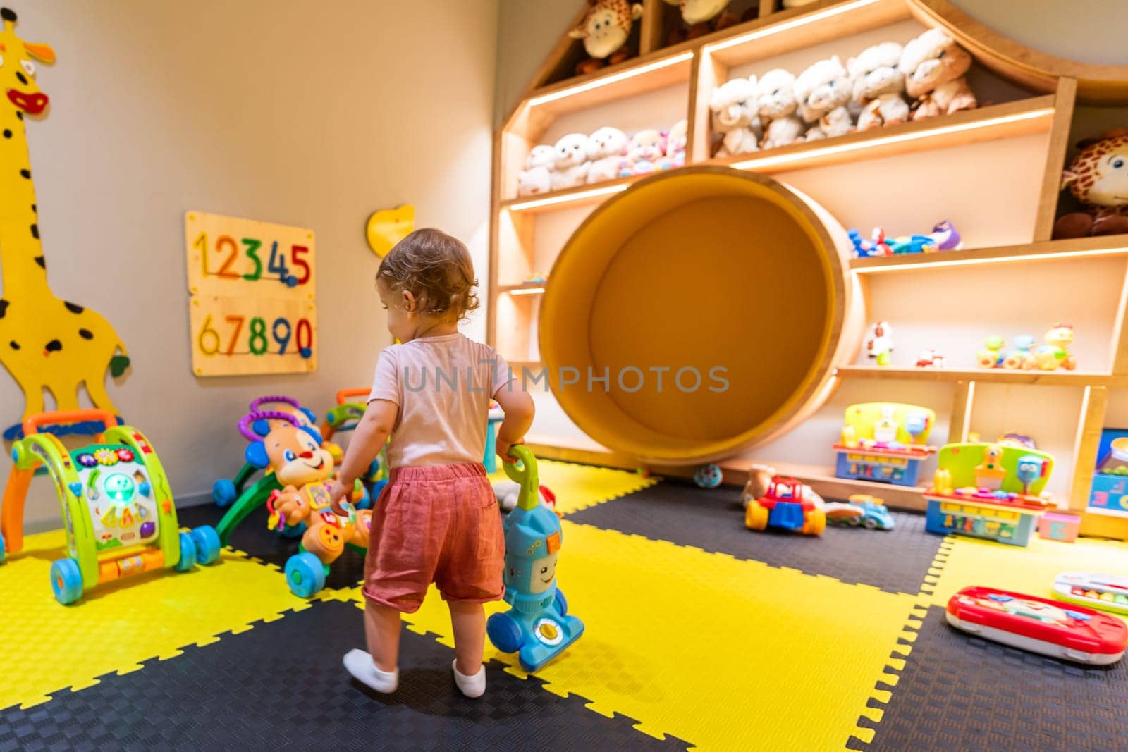Curious child exploring pretend cleaning with a toy vacuum cleaner in a fun and educational playroom