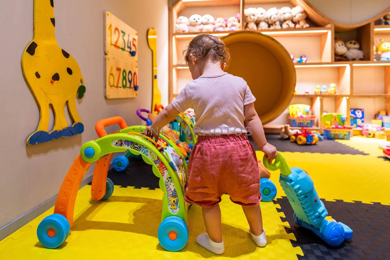 Child engaging with interactive toys and educational games in a bright play area