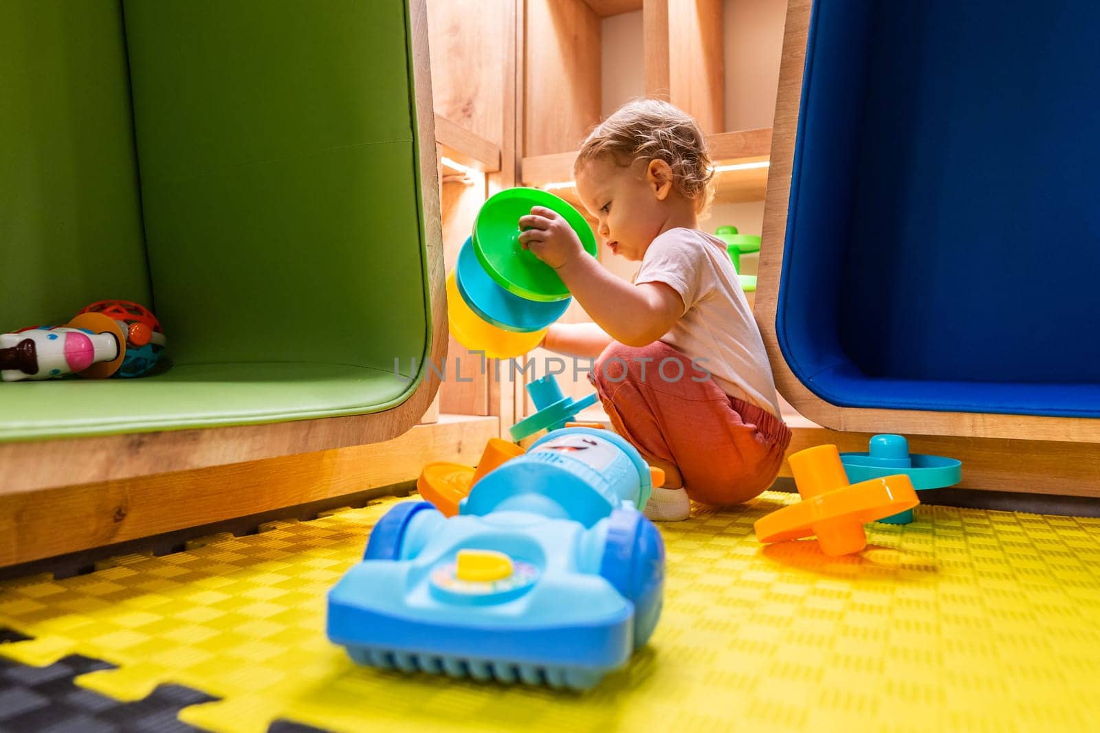 Child exploring activity toys and shelves in a vibrant indoor playroom for creative playtime