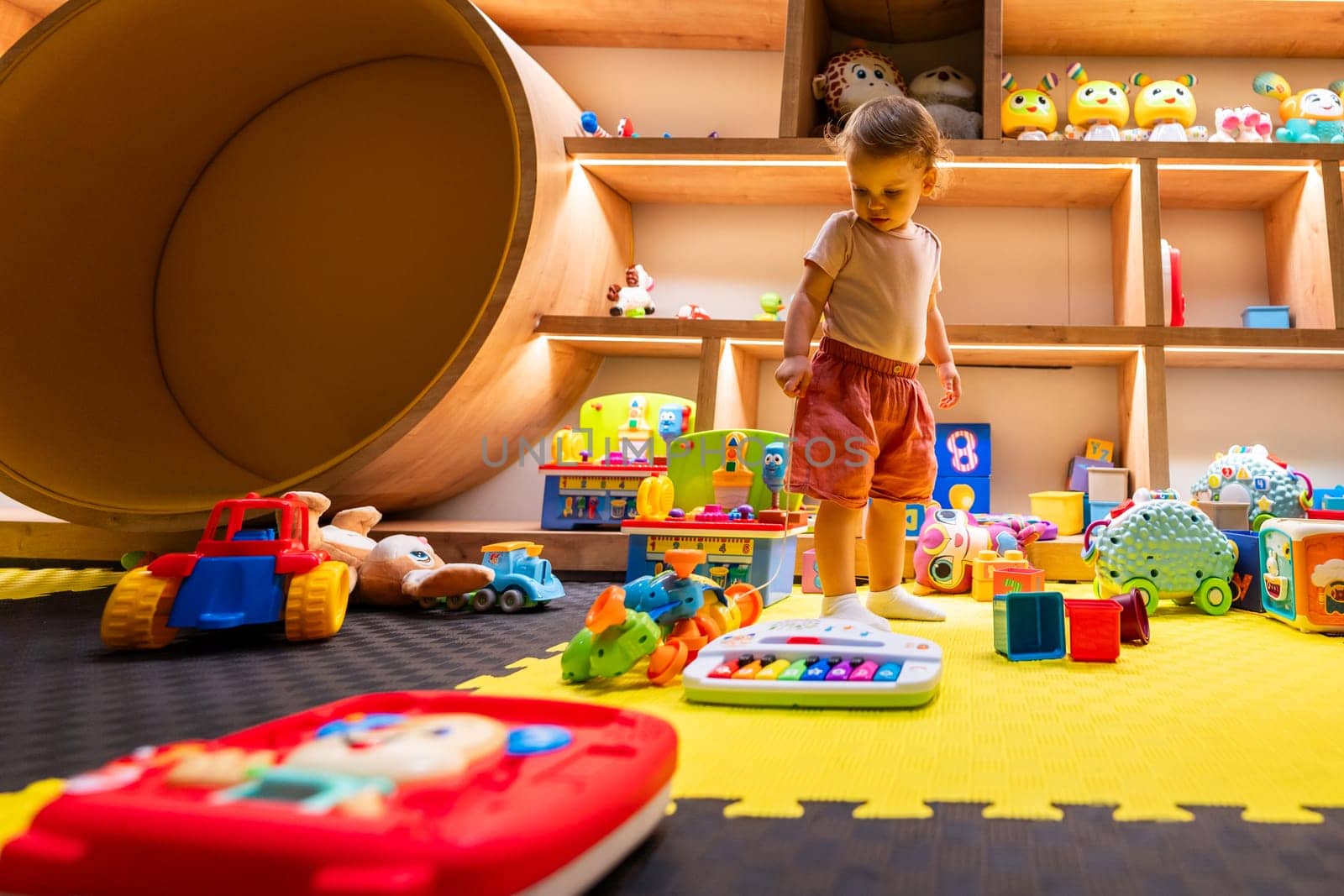 Toddler surrounded by colorful toys in an engaging indoor playroom designed for fun, learning, and creative exploration