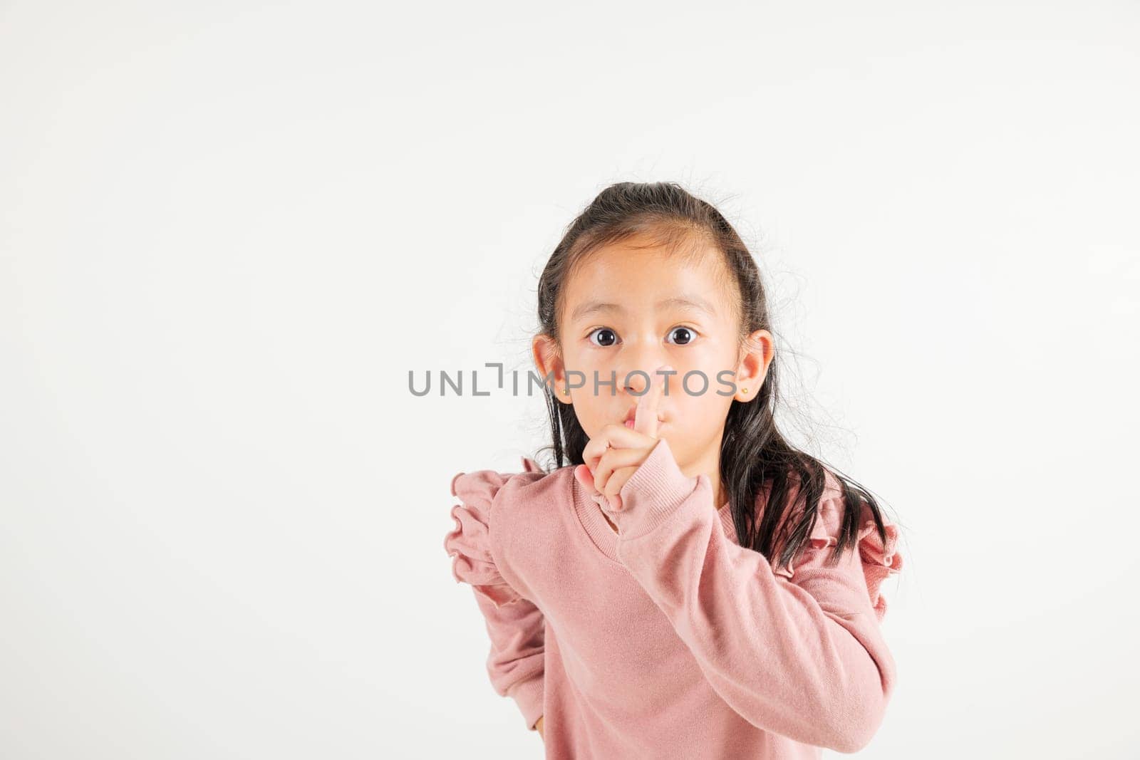 Young kid girl making finger on lips mouth silent quiet gesture, Happy Asian kindergarten child marking silence for stop quiet, mute studio shot isolated on white background with copy space