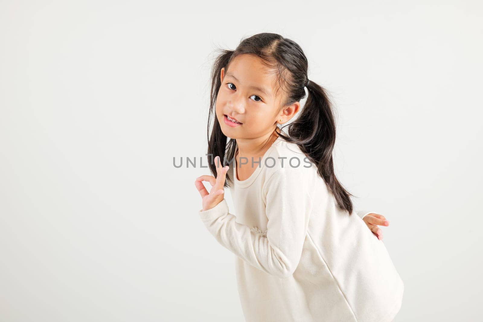 Exuberant young kid girl showcases the OK sign with an optimistic smile, conveying agreement and positivity isolated on a white background, ideal for your text customization. kindergarten child smile