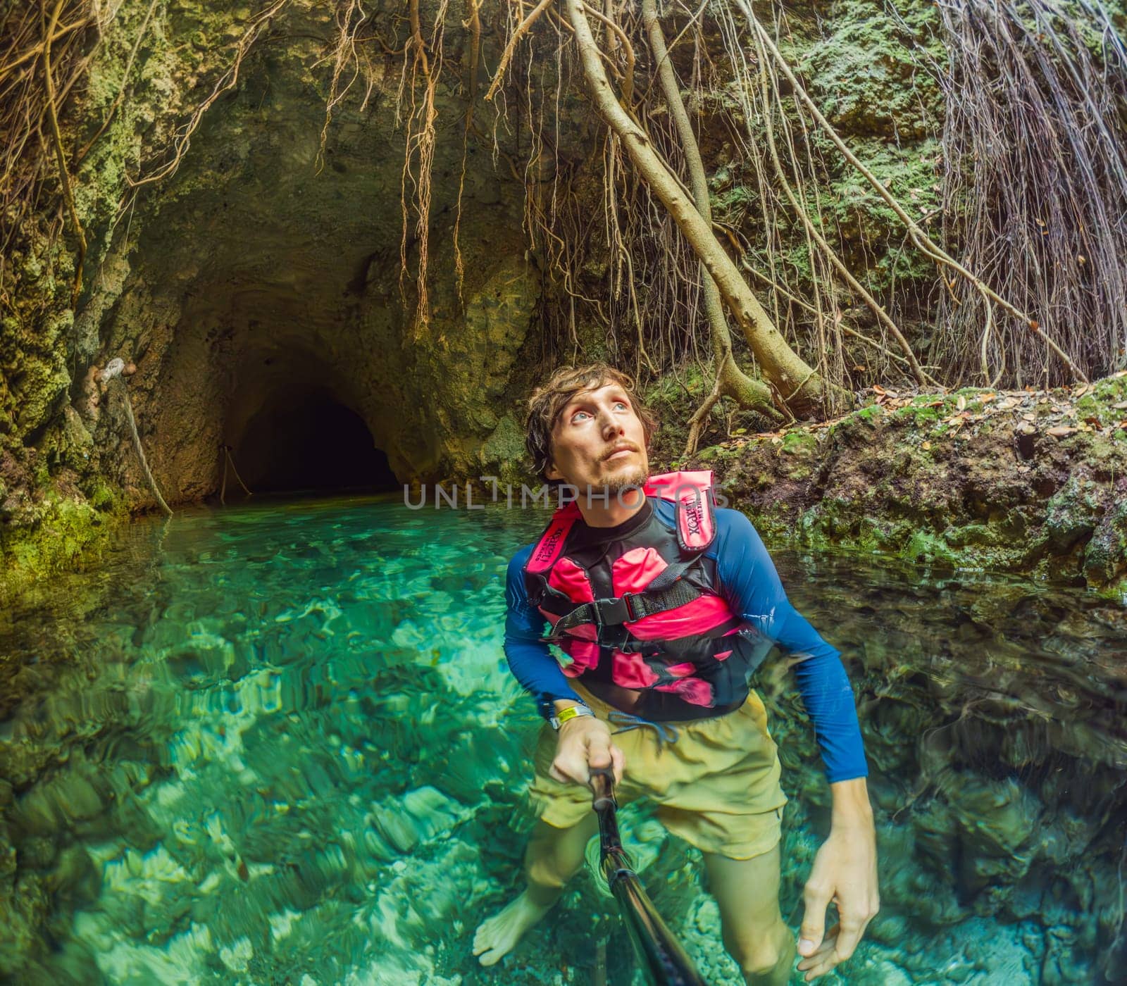 09.12.24, Playa Del Carmen, Mexico: Man tourist standing in the water of a cenote at Xcaret park wearing a marked life jacket. Mexican tourism in natural parks. Adventure, relaxation, and eco-tourism concept in Quintana Roo.