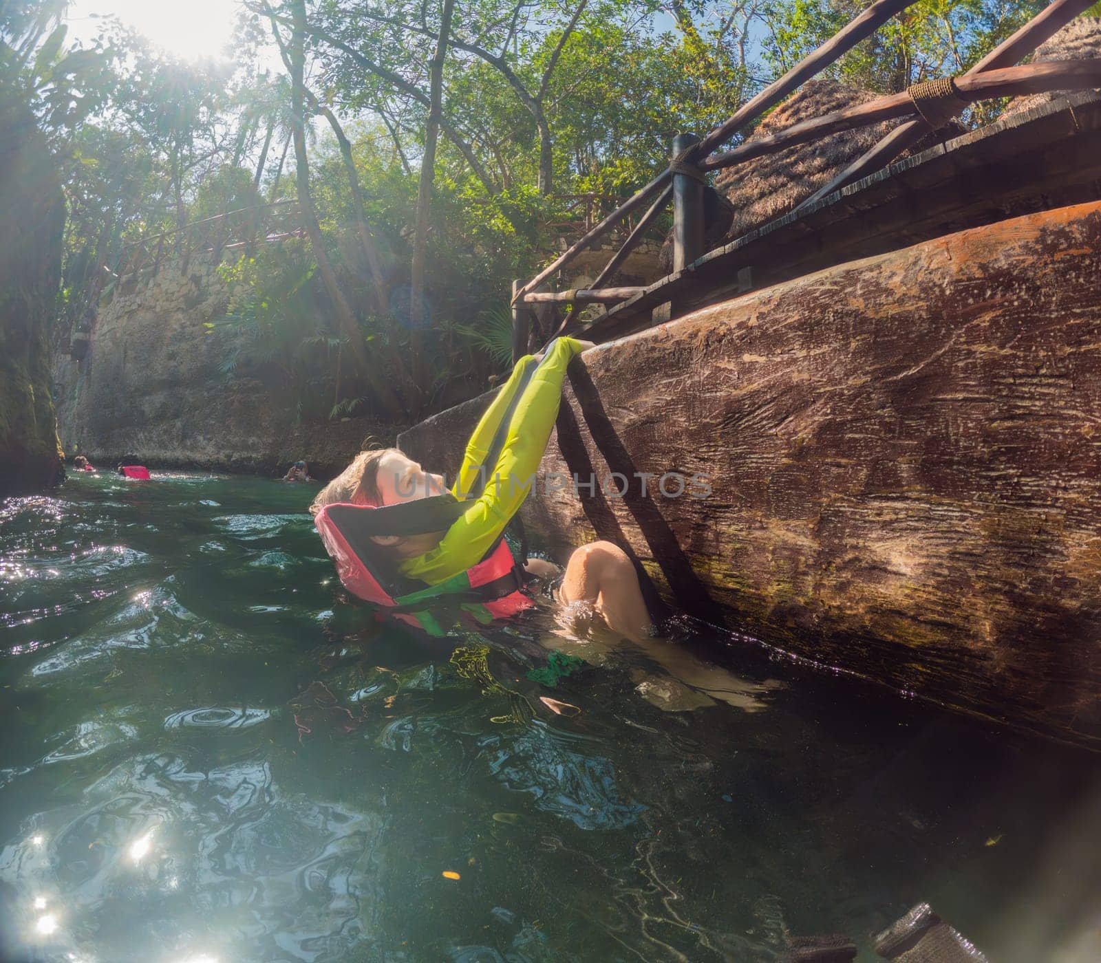 09.12.24, Playa Del Carmen, Mexico: Boy tourist in the water of a cenote at Xcaret park wearing a marked life jacket. Mexican tourism in natural parks. Adventure, childhood exploration, and eco-tourism concept in Quintana Roo.