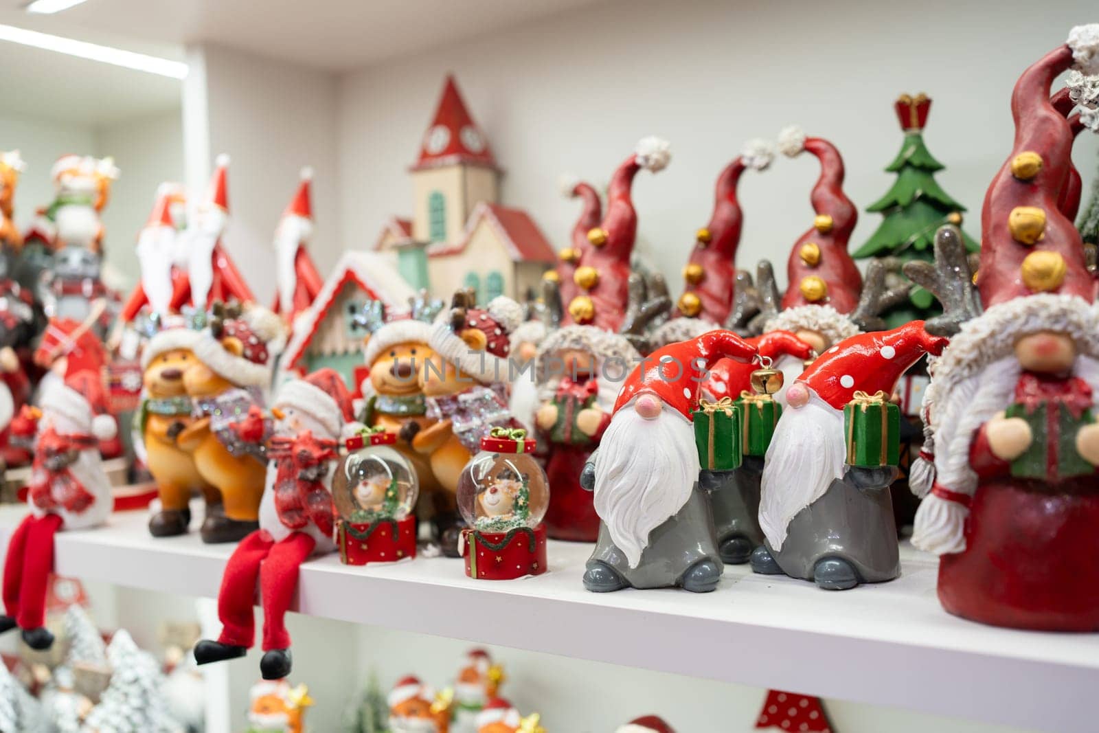 Variety of artistic Christmas figurines are beautifully displayed on shelves in store, featuring festive characters like Santa, snowmen and reindeer, creating warm and cheerful holiday atmosphere