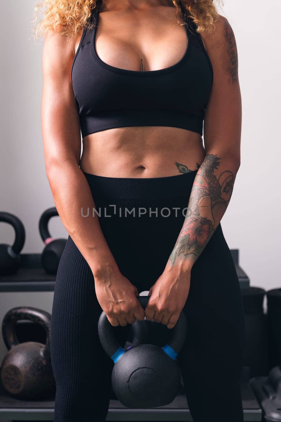 unrecognizable powerful sports woman with tattoos doing exercise with heavy kettlebell during functional training in gym, concept of fitness and active lifestyle