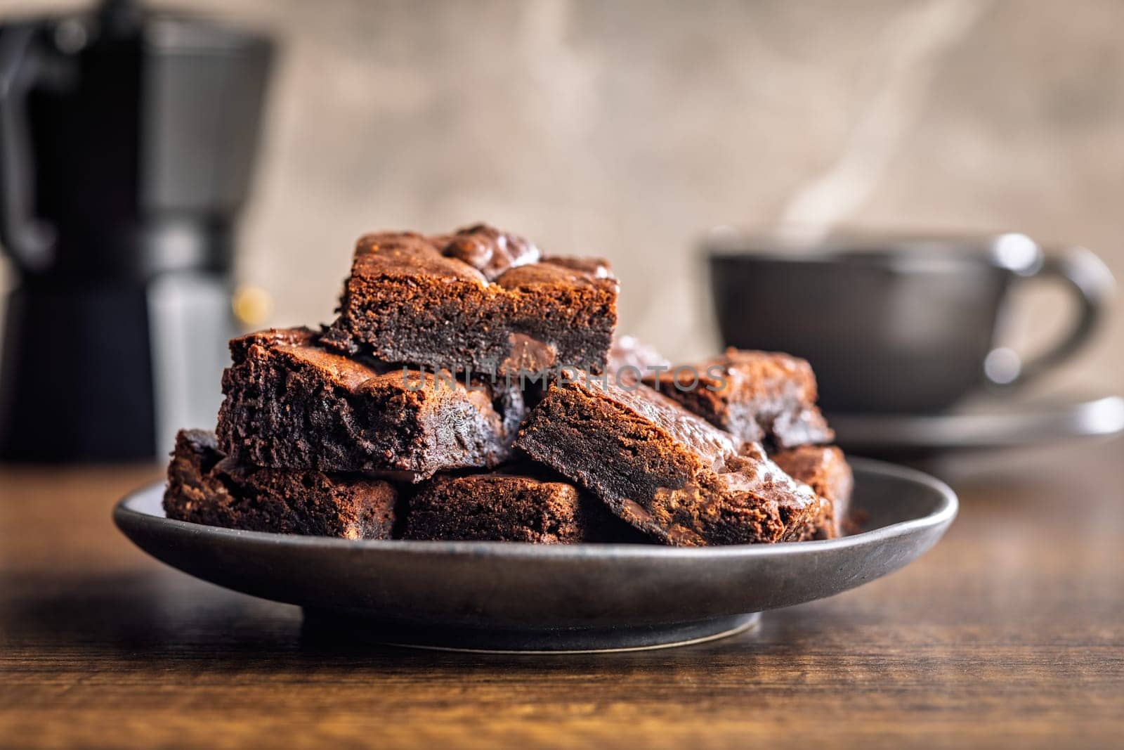 Homemade chocolate brownies on plate on a wooden table.
