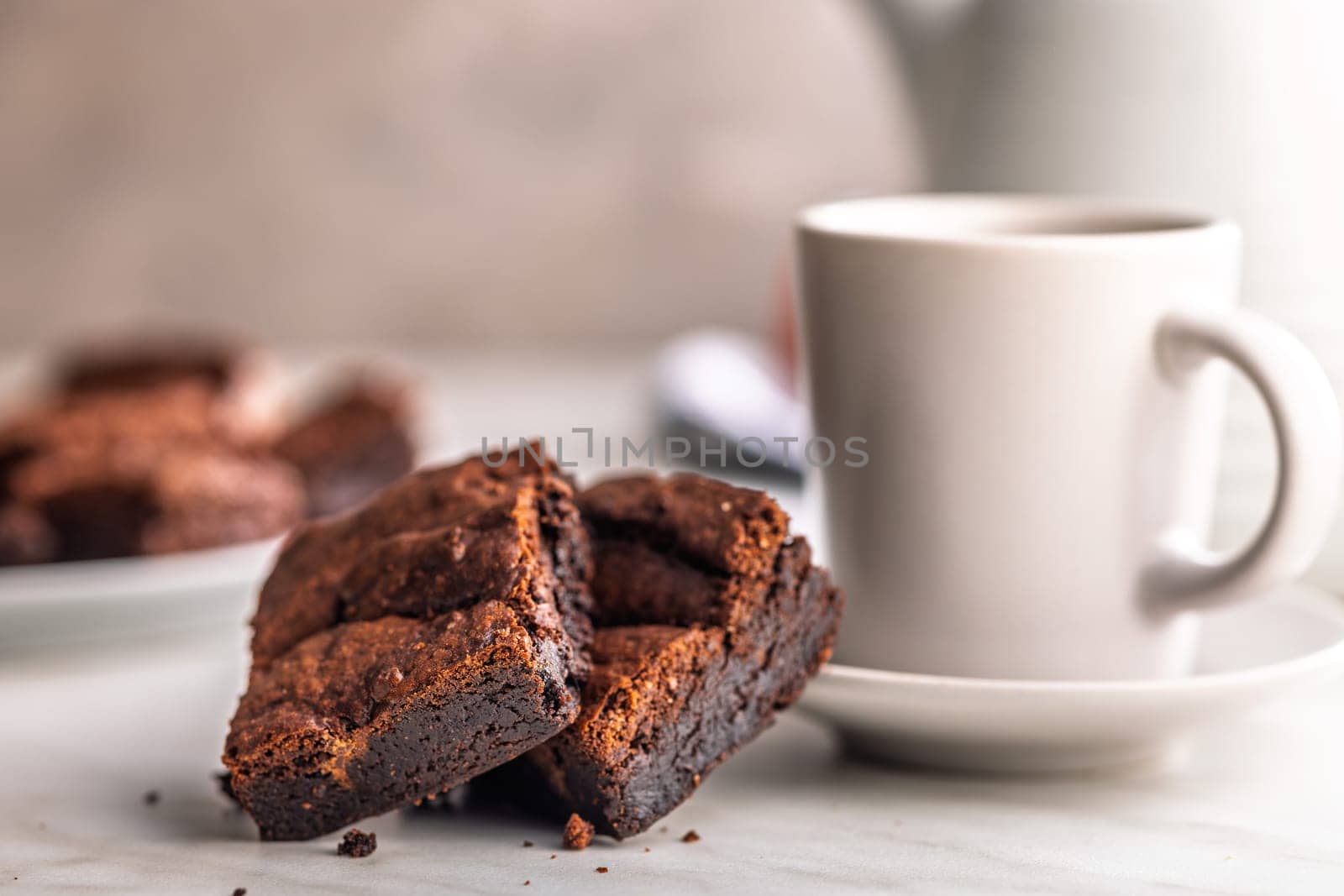 Homemade chocolate brownies and coffee cup on a kitchen table.