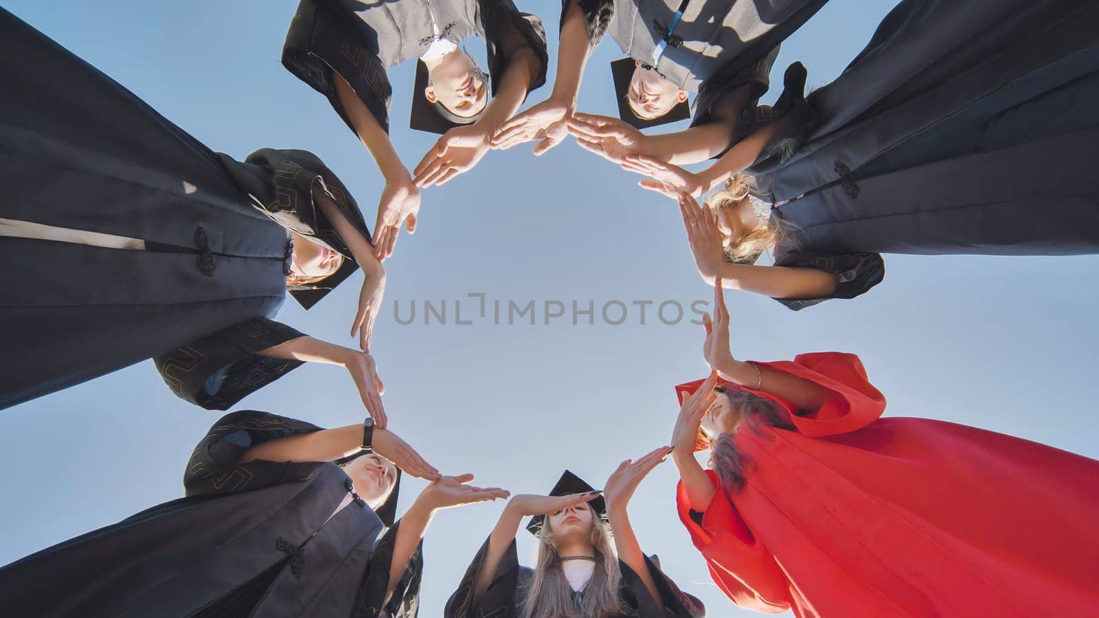 College graduates make a large circle from their hands