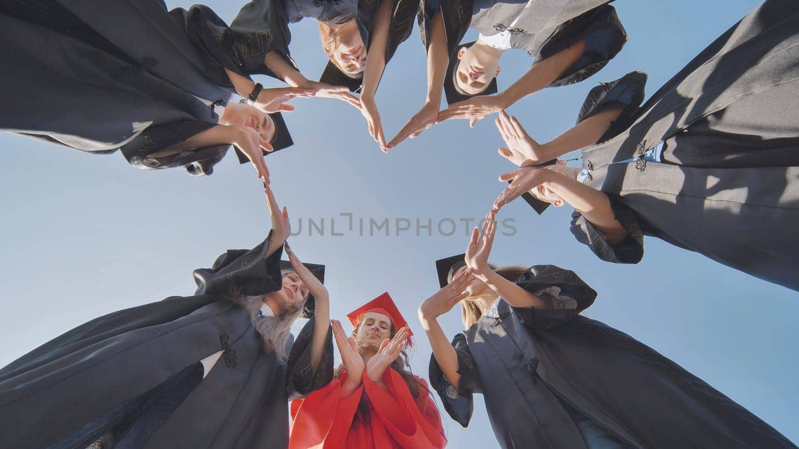 Students graduating from the college make a heart out of their hands