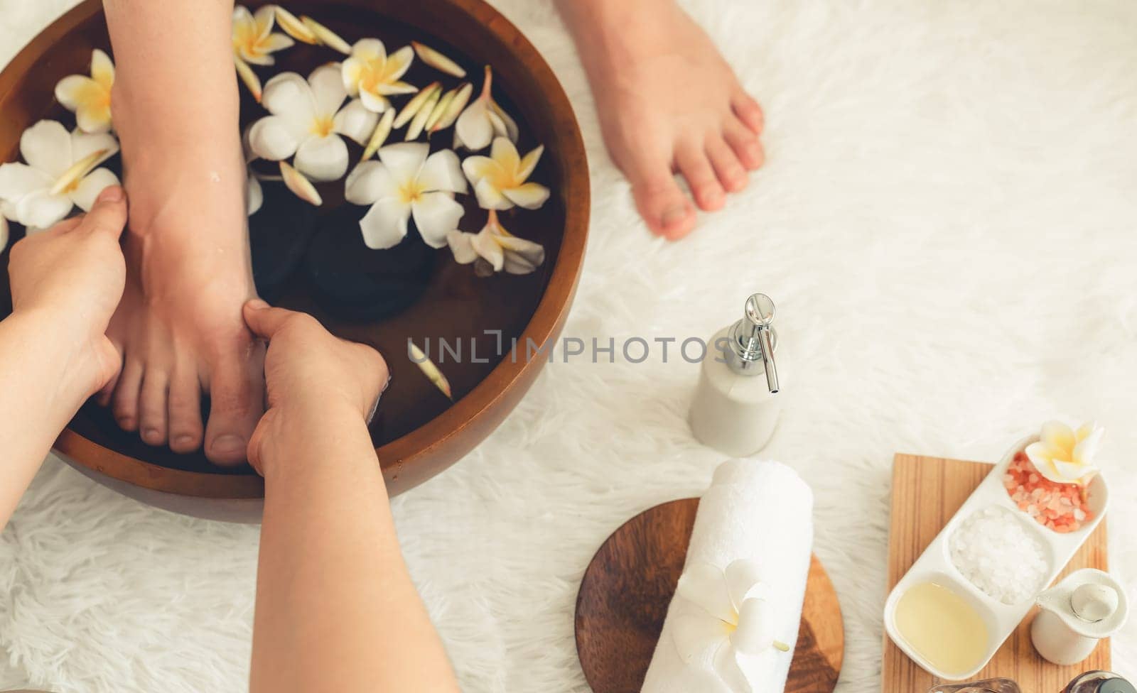 Woman indulges in blissful foot massage at luxurious spa salon while masseur give reflexology therapy in gentle day light ambiance resort or hotel foot spa. Quiescent