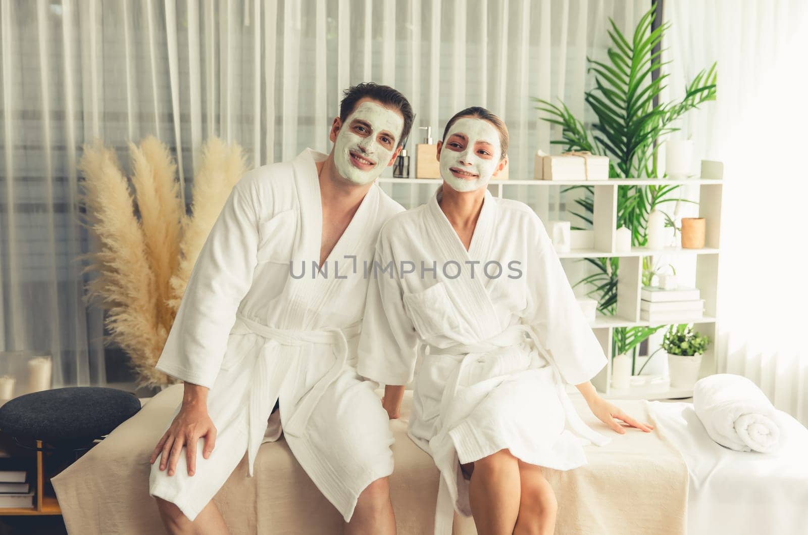 Blissful couple in bathrobe with facial cream mask enjoying serene ambiance of spa salon resort or hotel during holiday. Pampering face spa and skincare treatment with essence relaxation. Quiescent