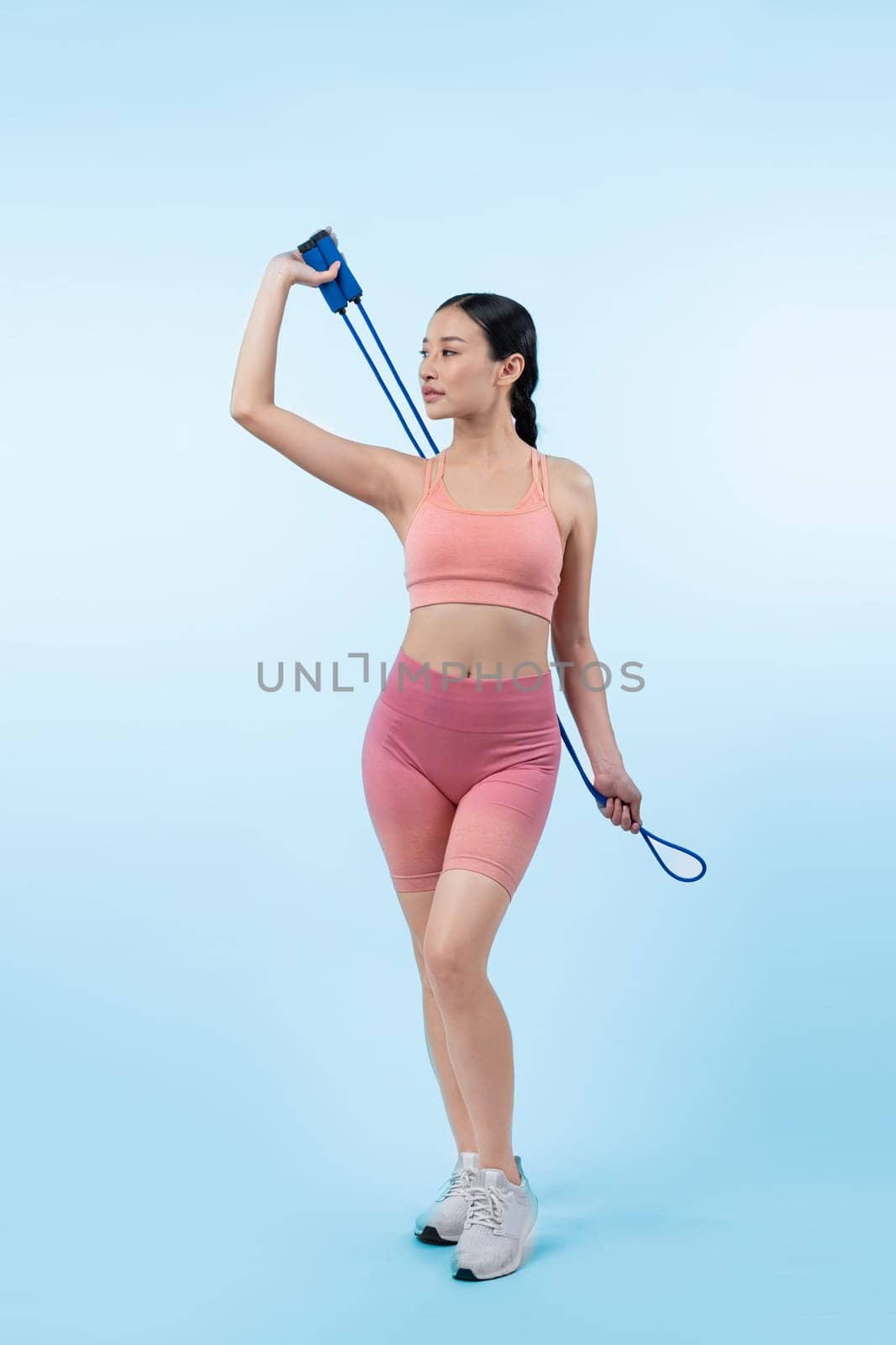 Young energetic asian woman in sportswear with jumping or skipping robe posing portrait in studio shot on isolated background. Cardio exercise tool and healthy body care lifestyle. Vigorous