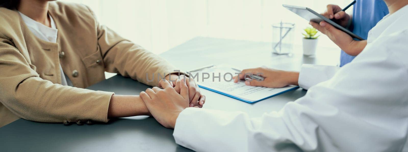 Doctor show medical diagnosis report and providing compassionate healthcare consultation while holding young patient hand for being supportive and professional in doctor clinic office. Neoteric