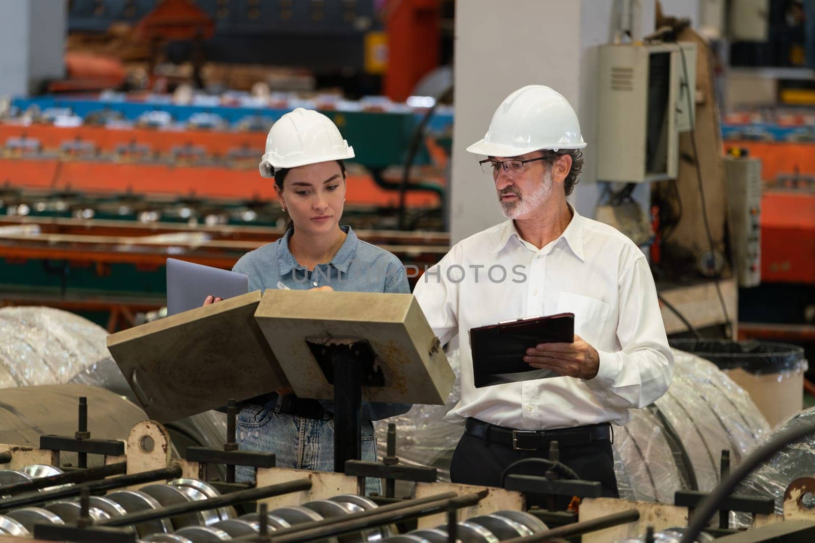 Factory engineer with assistant using laptop inspect factory. Exemplifying by biancoblue