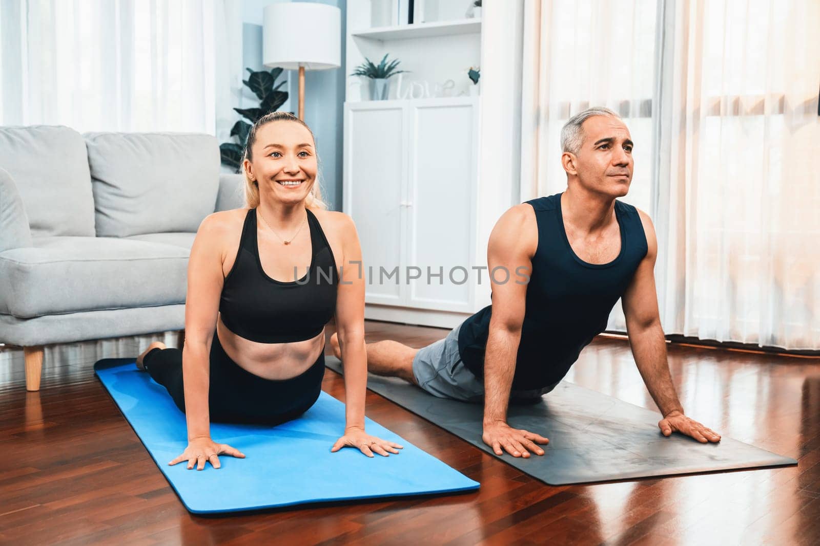 Happy active senior couple in sportswear doing yoga. Clout by biancoblue