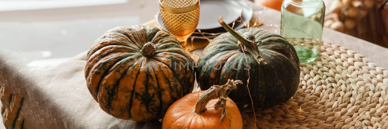 Autumn interior: a table covered with dishes, pumpkins, a relaxed composition of Japanese pampas grass. Interior in the photo Studio. Close - up of a decorated autumn table