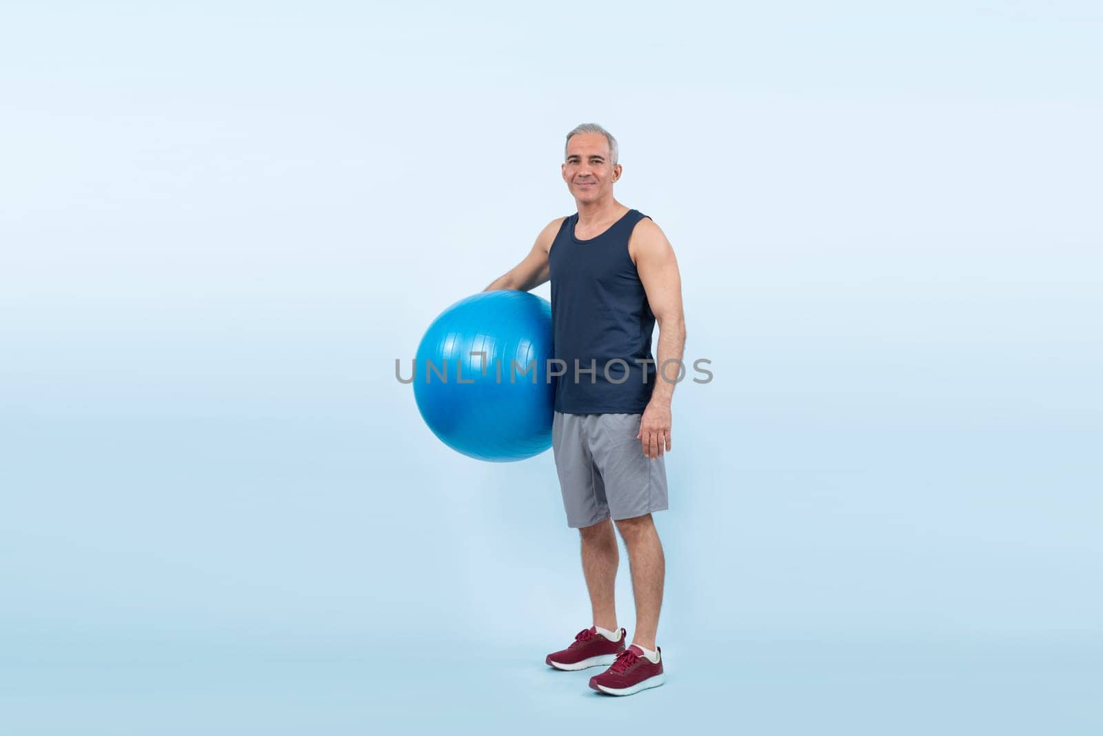 Full body length shot athletic and sporty senior man with fit ball. Clout by biancoblue