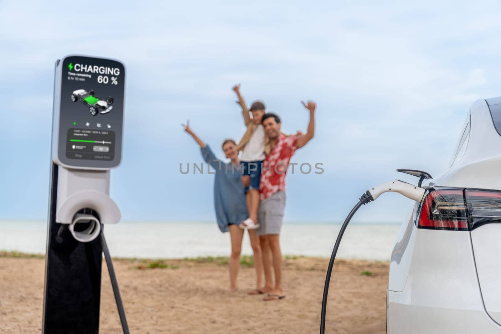 Alternative family vacation trip traveling by the beach with electric car recharging battery from EV charging station with blurred cheerful and happy family enjoying the seascape background. Perpetual