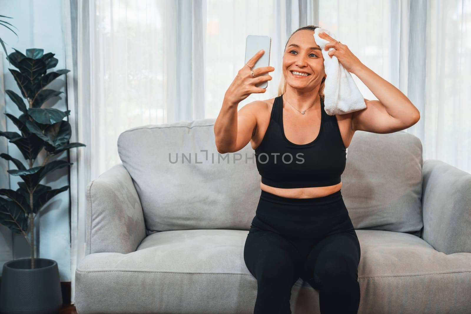 Active and sporty senior take selfie with smartphone after finishing home workout exercise. Healthy and fit body lifestyle for pensioner after retirement workout exercising at home. Clout