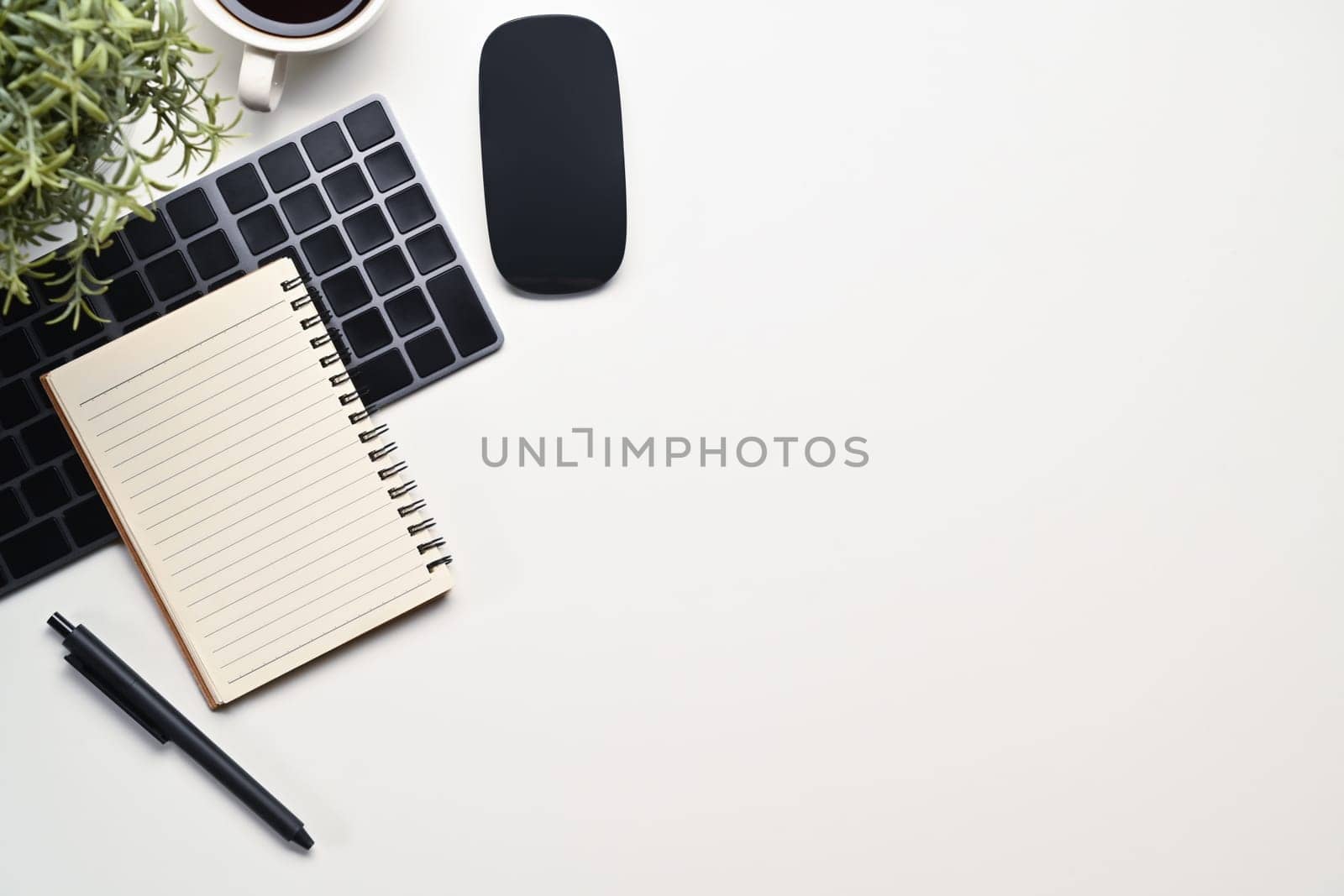 White office desk with wireless keyboard, mouse, notepad and coffee cup. Top view with copy space for text by prathanchorruangsak