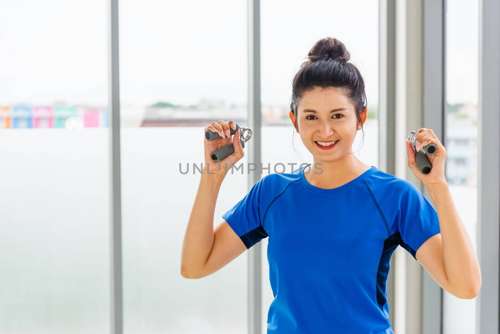 Asian lifestyle young woman in sportswear holding the hand grip exercise indoor yoga studio, fit sport healthy workout exercise