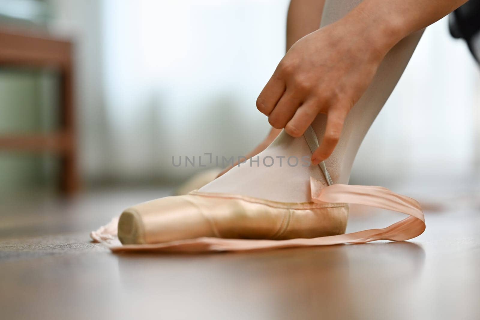 Closeup ballerina tying pointe shoes in dance studio. Art, dance, people and inspiration concept by prathanchorruangsak