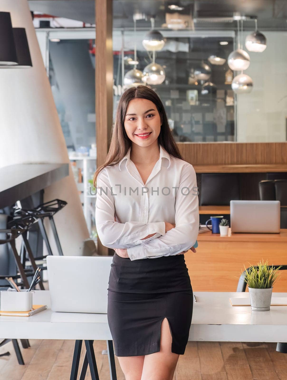 asian businesswoman standing with arms looking at camera in the office..