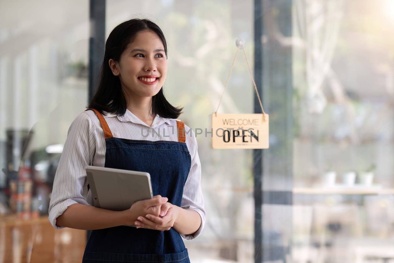 Opening a small business, A Happy Asian woman in an apron standing near a bar counter coffee shop, Small business owner, restaurant, barista, cafe, Online, SME, entrepreneur, and seller concept.