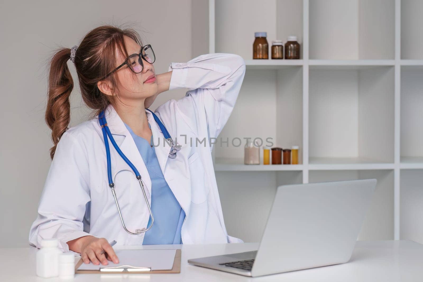 Stressed young female doctor looking at laptop, work related chaos, worried about mistake at work The stressed-out, unhappy medical professional is tired of solving computer problems at work..