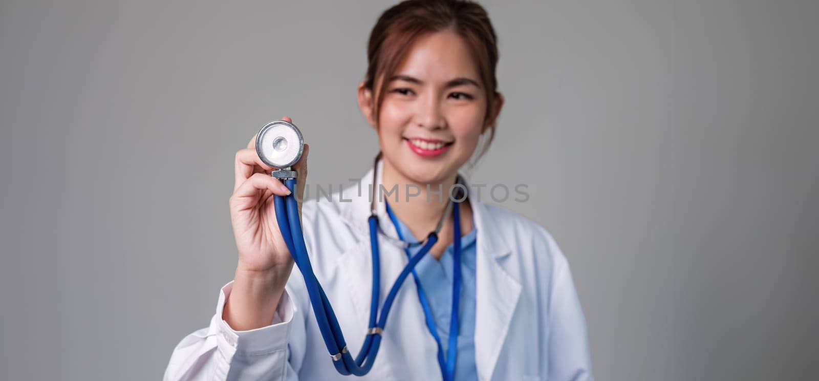Portrait of female doctor using stethoscope on flat background. health care concept Female doctor using equipment to check patient's health by wichayada