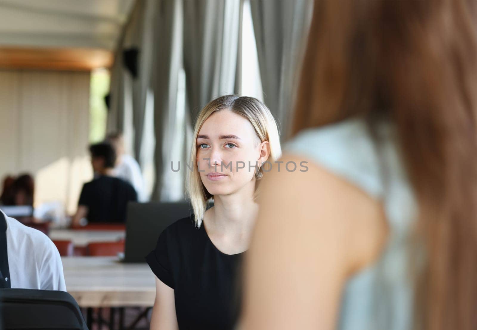 Beautiful smiling cheerful girl at workplace look at camera with colleagues group in background. White collar worker at cafe modern lifestyle client visit profession train concept