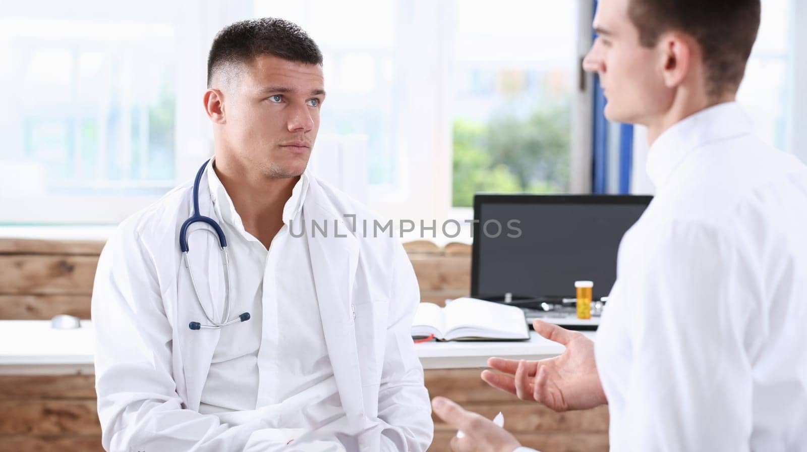 Handsome male medicine doctor with clipboard pad in hands examine patient and prescribe remedy. Exam visitor reception disease prevention ward round visit check 911 healthy lifestyle concept