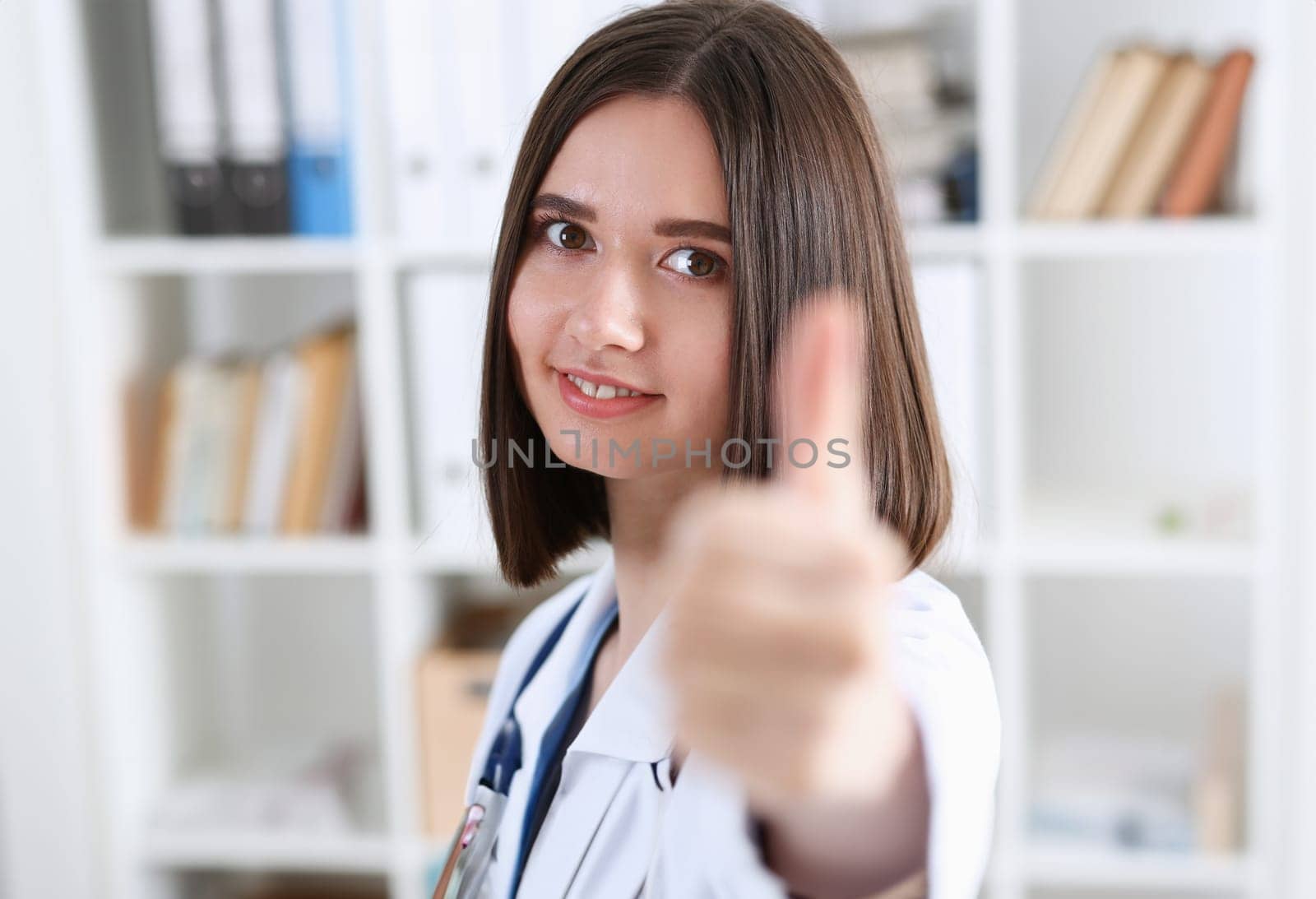 Smiling female doctor showing ok sign with thumb up at office portrait. High level work confident satisfied woman do like visit to clinic best occupation emergency help teamwork concept