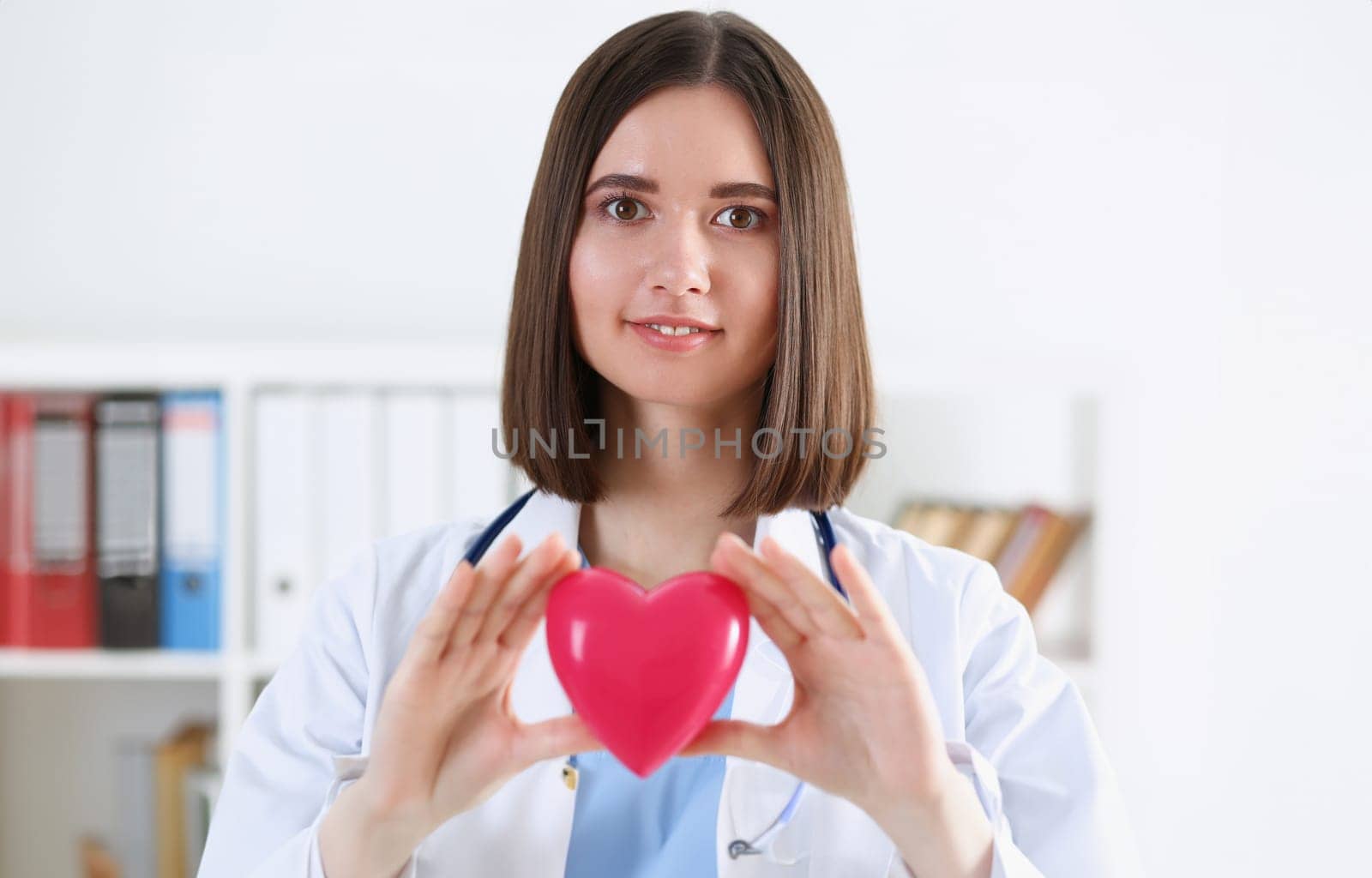 Female medicine doctor hands holding and covering red toy heart closeup. Cardio therapeutist student education physician make cardiac physical heart rate measure arrhythmia concept