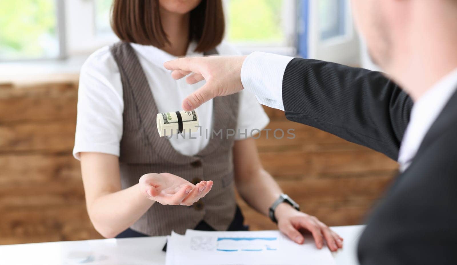 Businessman hands a cutlet out of money to a woman in the form of a bribe of salary. In an envelope dollar equivalent from hand to hand.