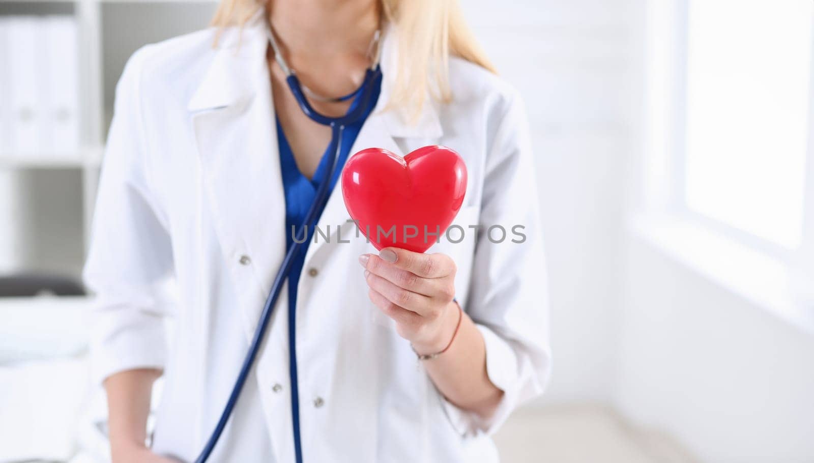 Female medicine doctor hands holding and covering red toy heart closeup. Cardio therapeutist student education physician make cardiac physical heart rate measure arrhythmia concept