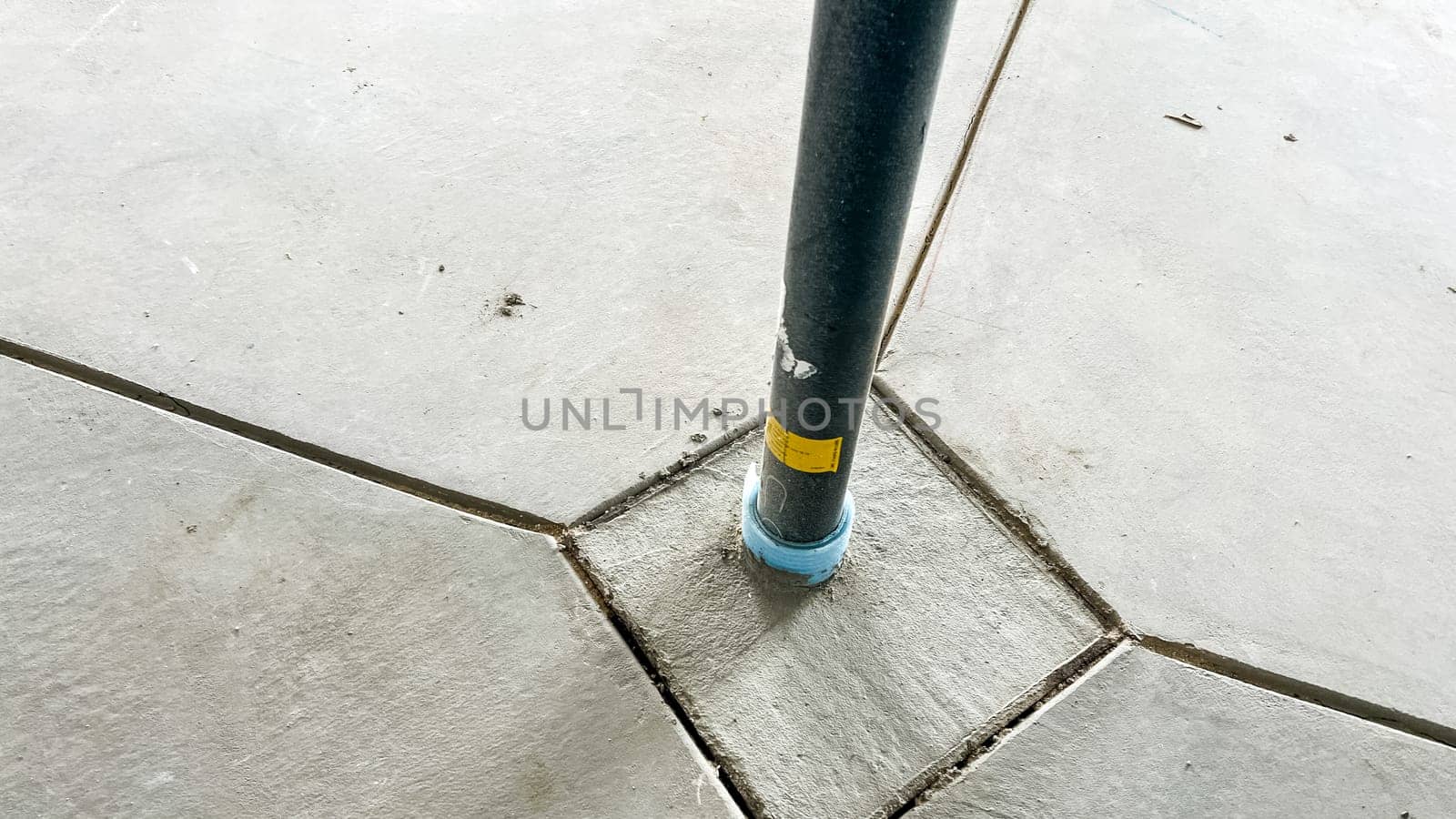 Castle Pines, Colorado USA - January 18, 2023-Close-up of a metal structural support post anchored into a concrete basement floor in a new single-family home under construction. The post is securely positioned at the intersection of neatly cut concrete sections, highlighting construction precision.