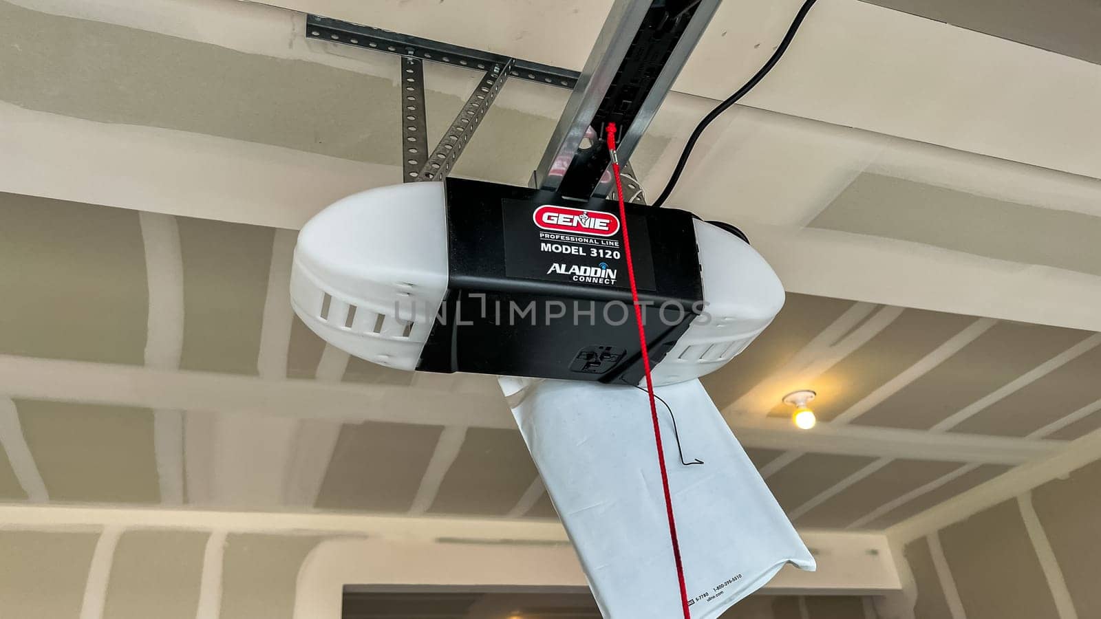 Castle Pines, Colorado USA - January 18, 2023-Close-up view of a Genie garage door opener installed in the garage of a new single-family house under construction. The partially finished garage features drywall and ceiling lighting, highlighting ongoing progress in home building.